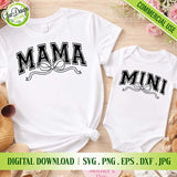 Flat lay mockup of matching white t-shirt with 'MAMA' and baby onesie with 'MINI' varsity designs with bows, arranged with sunglasses, sandals, a straw bag, and flowers on a wooden surface