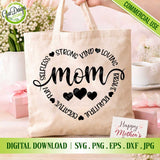 Inspirational Selfless Strong Kind Loving Mom SVG heart typography design on a natural canvas tote bag mockup surrounded by white flowers and a Mother's Day card