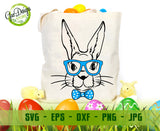 Beige canvas tote bag mockup featuring a printed black line art bunny face wearing blue glasses and a blue polka dot bowtie, sitting standing and filled with Easter eggs; background with two tiny yellow chicks and colorful eggs
